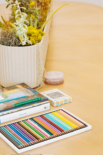 Coloring pencils and coloring books for adults laid out on the Renovaré table